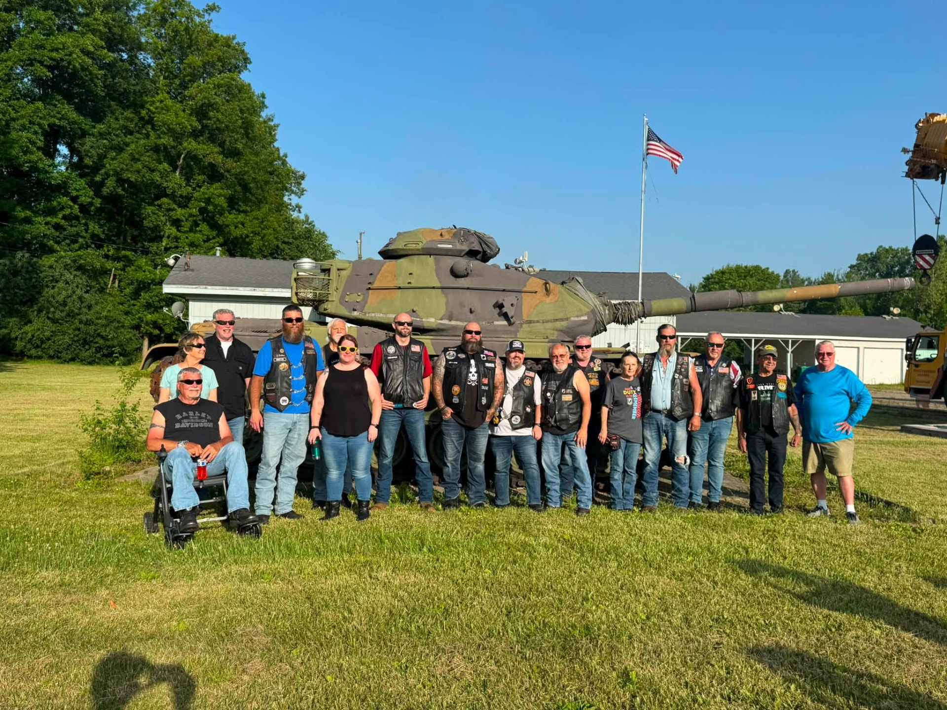 Sanford American Legion Riders members gathered in front of the military tank they escorted to Post #443 for permanent display, beneath an American flag